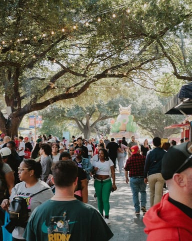 Lively outdoor market under oak trees with string lights