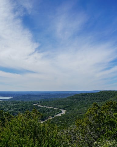 Hiker on a rocky Hill Country trail with cedar trees