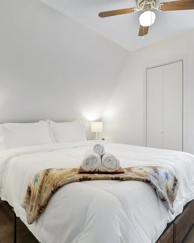 Bright white king bedroom with wood-beam ceiling
