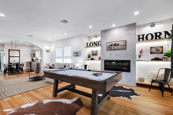 Longhorn living room with pool table, fireplace, and open kitchen beyond